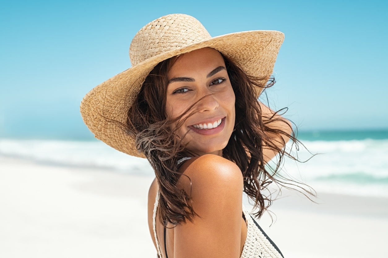 Beautiful girl with a straw hat at the beach